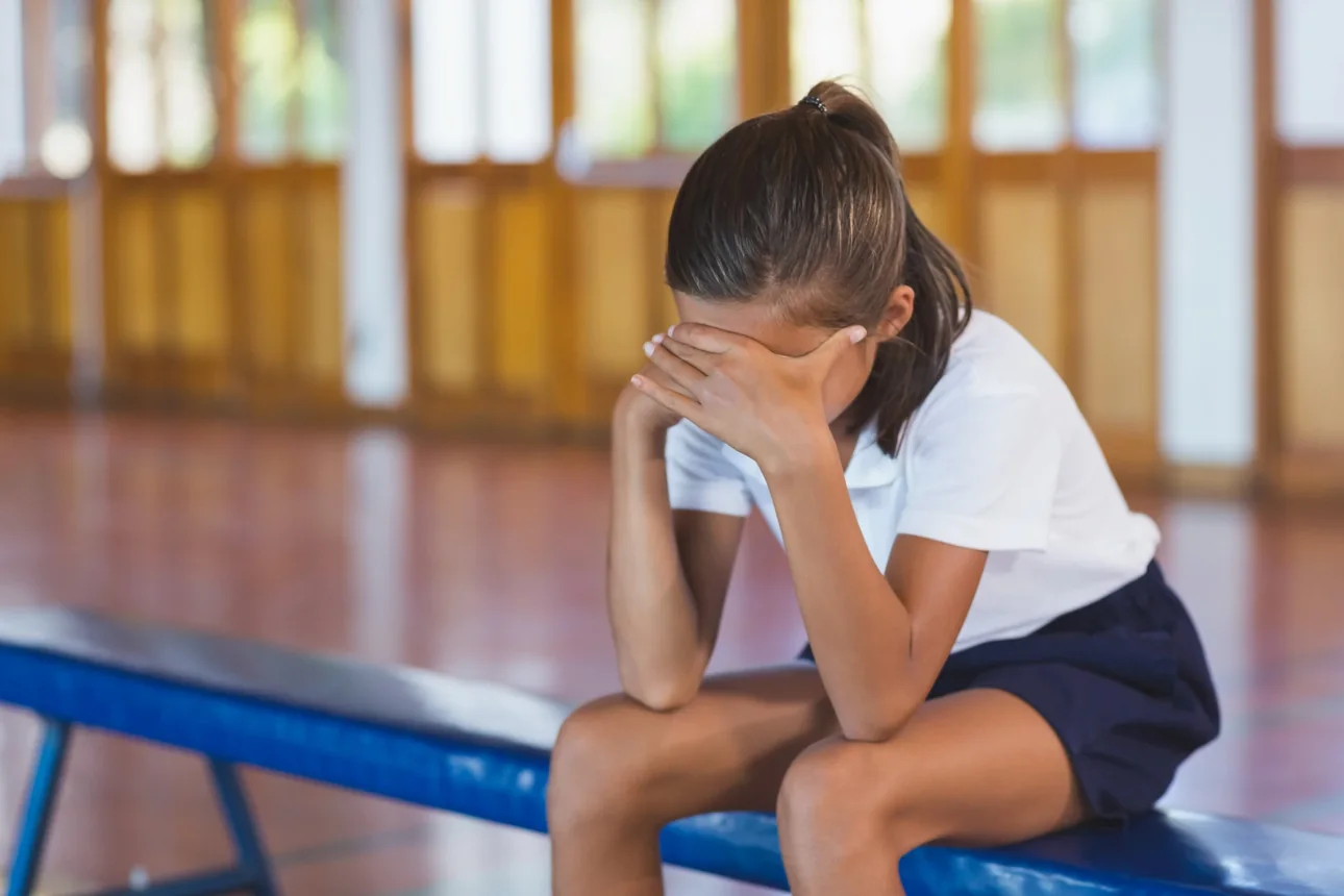 Discouraged young athlete sitting on a gym bench